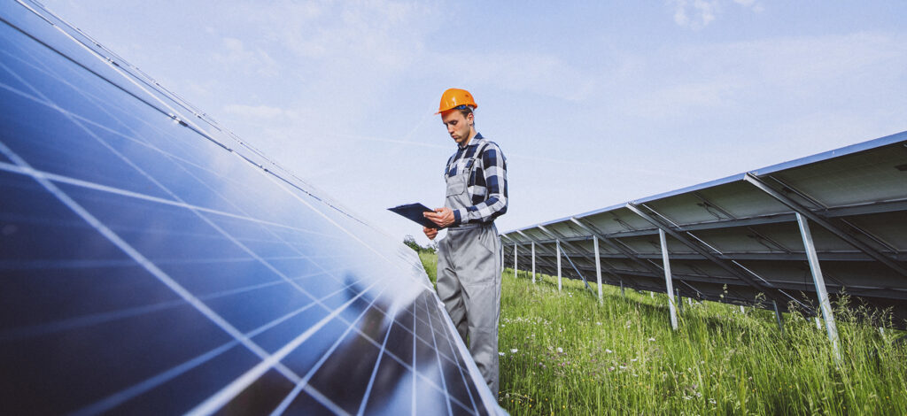 Man Worker In The Firld By The Solar Panels